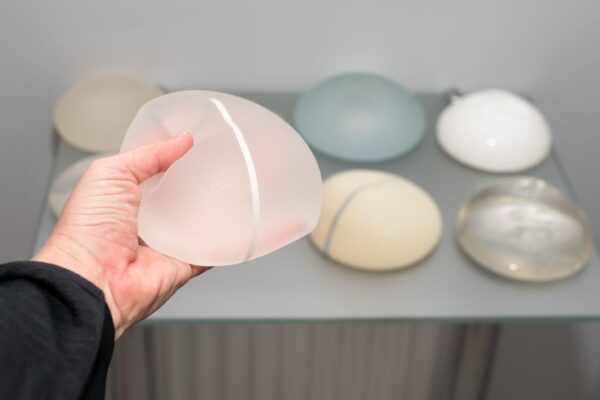 multiple breast implant options on a table with someone holding one of them