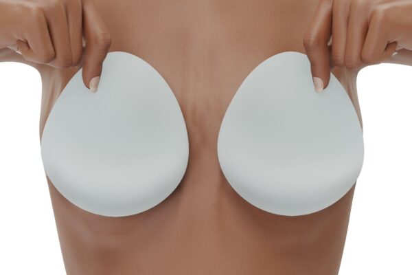 woman covers her breasts with silicone implants