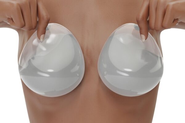 woman covers her breasts with smooth saline implants