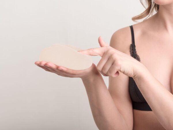 woman in bra holding breast implant