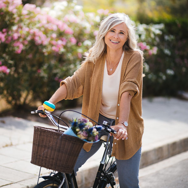 Smiling senior woman having fun riding vintage bike in spring
