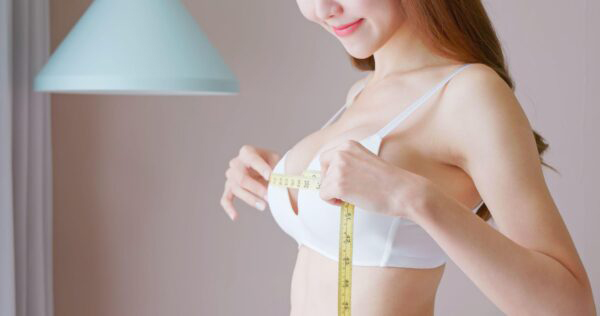 Woman measuring breasts with measuring tape