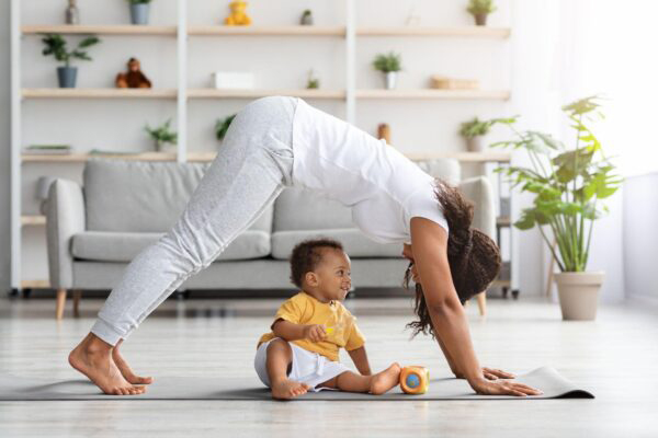 Young mother practicing yoga at home with her infant son