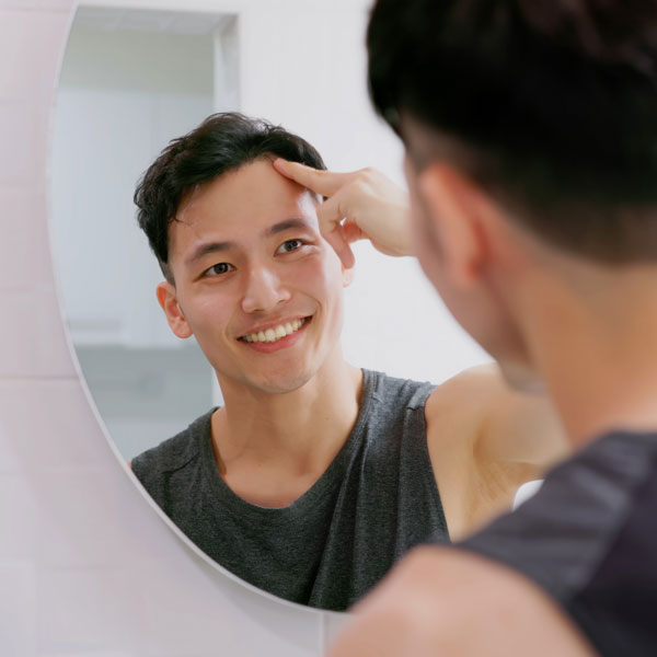 young man touching hair and looking at himself in the mirror